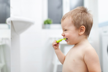 Adorable child learing how to brush his teeth