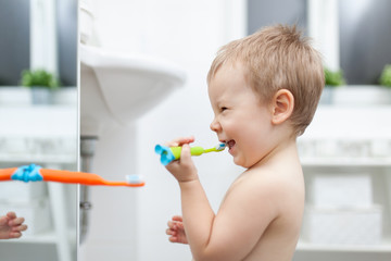 Adorable child learing how to brush his teeth