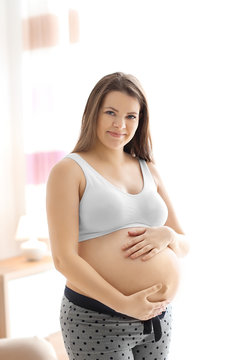 Pregnant young woman after application of body cream on blurred background