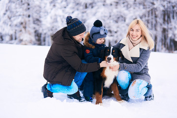 Fototapeta na wymiar The mother,father,son and dog sitting on the snow