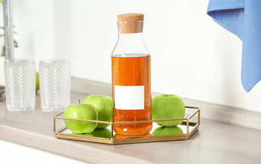 Bottle with juice and fresh apples in kitchen