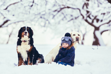 Fototapeta na wymiar The small boy and dogs sitting on the snow