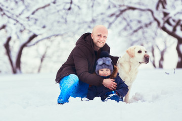 The beautiful father ,son and dog sitting on the snow
