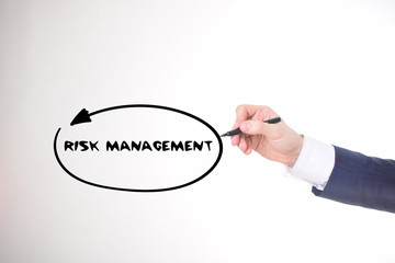 The businessman writes a black marker inscription:RISK MANAGEMENT