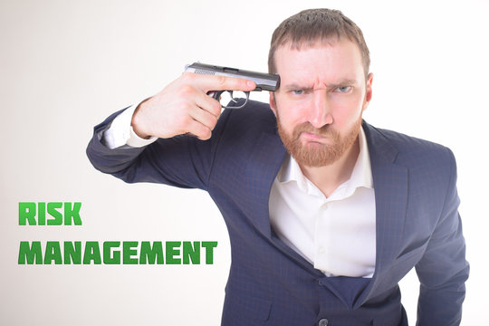 The businessman holds a gun in his hand and shows the inscription:RISK MANAGEMENT