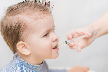 mom gives the baby fish oil through a syringe