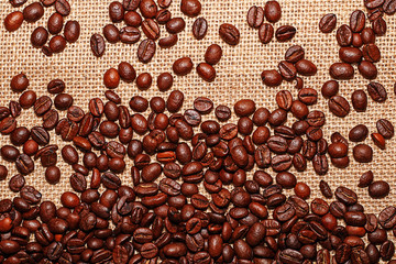 Grains of tasty roasted coffee on the background of cloth burlap