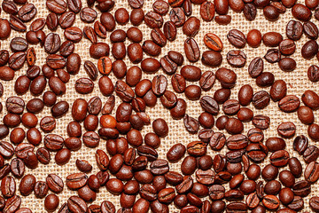 Grains of tasty roasted coffee on the background of cloth burlap