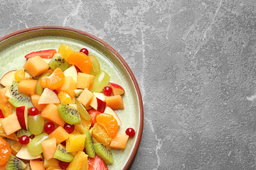 Plate with fresh cut fruits on table, top view