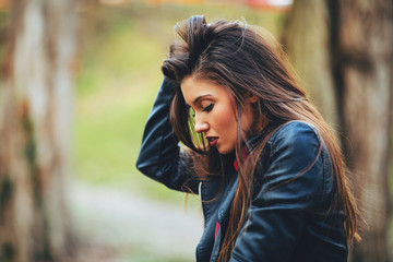 Portrait of a beautiful young woman in a leather jacket in the park