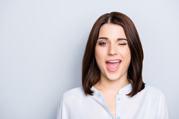 Close up portrait of nice, modern, trendy woman having short hair and open mouth, blinking with eye, isolated on grey background