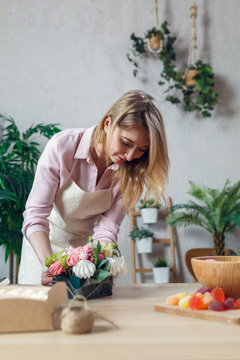 Image of florist composing bouquet at table on background of flowers