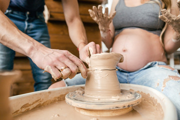 Obraz na płótnie Canvas Close-up of the couple's hand makes a clay vase on a Potter's wheel