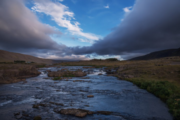 A river running amid hilly terrain. Evening light. Iceland.
