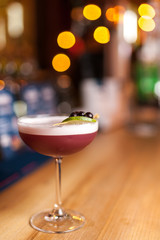 Red cocktail on the bar, blurred background.