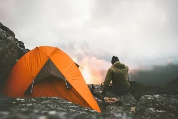 Foto auf Acrylglas Camping Alleinreisender Mann, der den Sonnenuntergang in den Bergen genießt und in der Nähe von Zelt Campingausrüstung im Freien sitzt Reiseabenteuer Lifestyle-Konzept Wandern Fernweh-Urlaub
