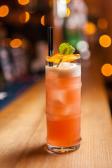 Orange cocktail with dried orange on the bar, blurred background.