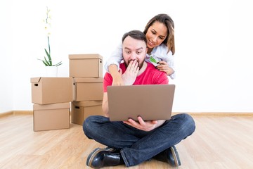 Happy family after moving to a new house choose furniture in the online store sitting on the floor with boxes of things