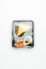 top view of closed plastic lunch box with sandwich and vegetables isolated on white