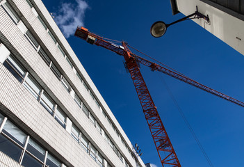 looking up at red construction tower crane in a city 
