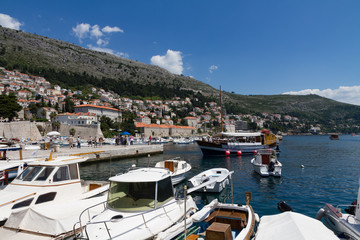 Fototapeta na wymiar Dubrovnik Stadt mit Rundweg, Hafen, Dächer und Kreuzfahrt Schiffe am Meer strahlend blauen Himmel
