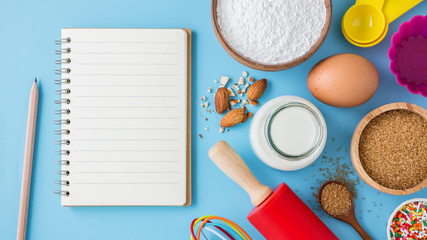 Baking ingredients and utensils with blank recipe book