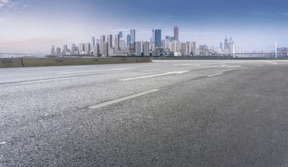 The empty asphalt road is along the modern commercial building in the Chinese city