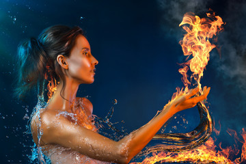 Conceptual art photography of a beautiful asian girl surrounded by burning water splashes holds on her hand fire flame