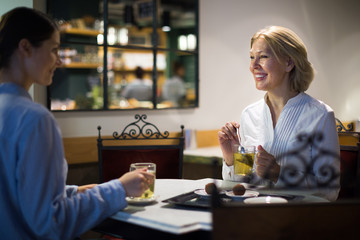 Young and mature woman drinking tea in cafe