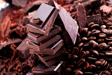 Broken dark chocolate, cocoa powder and coffee beans on a wooden table