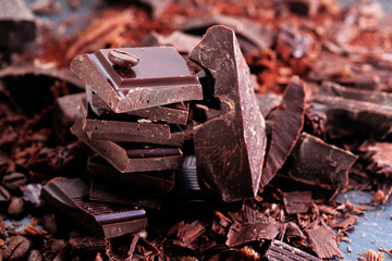 Broken dark chocolate, cocoa powder and coffee beans on a wooden table