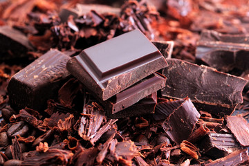 Broken dark chocolate, cocoa powder and coffee beans on a wooden table