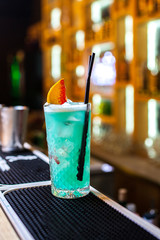 Blue, turquoise cocktail with lemon and streaks of syrup in bar
