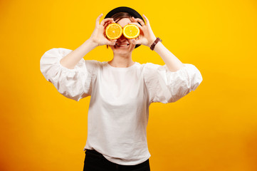 Cheerful woman holding two oranges on her eyes