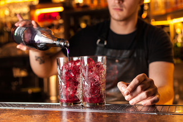 Close-up of expert bartender making red blueberry cocktail in bar
