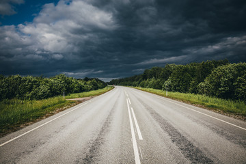 Storm clouds over Highway with green forest on the sides