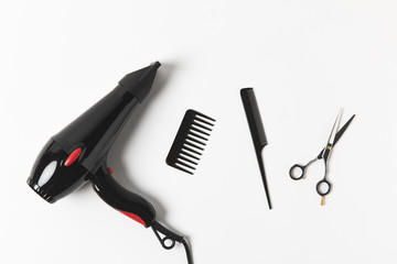 top view of hair dryer, combs and scissors, on white