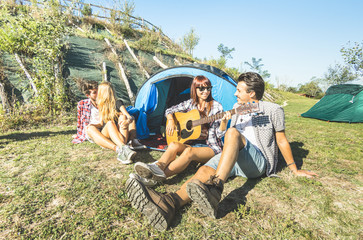 Friends group having fun outdoor cheering at picnic camp with vintage guitar - Young people enjoying summer time together at countryside party - Youth travel friendship concept - Warm bright filter