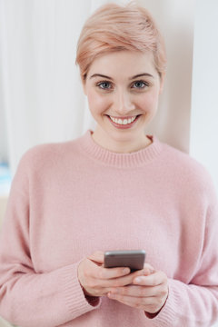 Happy attractive blond woman holding a smartphone