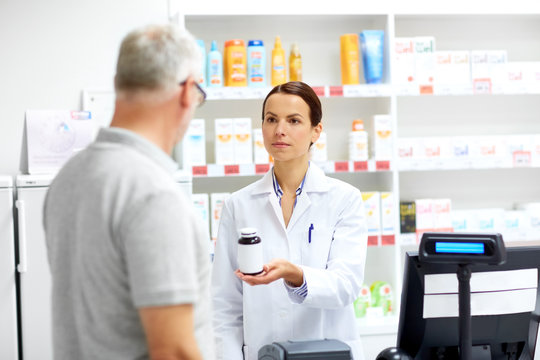 medicine, pharmaceutics, healthcare and people concept - apothecary and senior male customer buying drug at drugstore