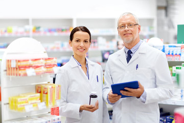medicine, healthcare and technology concept - apothecaries with tablet pc computer and medication...