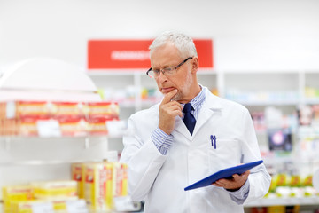 medicine, healthcare and technology concept - senior apothecary with tablet pc computer at pharmacy