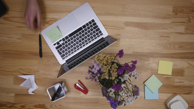 Businessman working on a laptop at office desk with paperwork and other objects around, top view