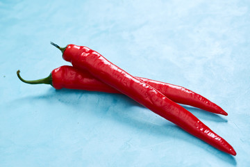 Burning fresh red hot pepper on a blue background, top view, close-up