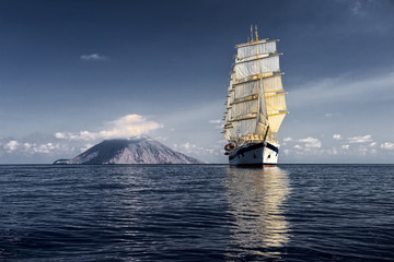 Sailing ship on the background of the island with a volcano. Cruises. Yachting. Sailing