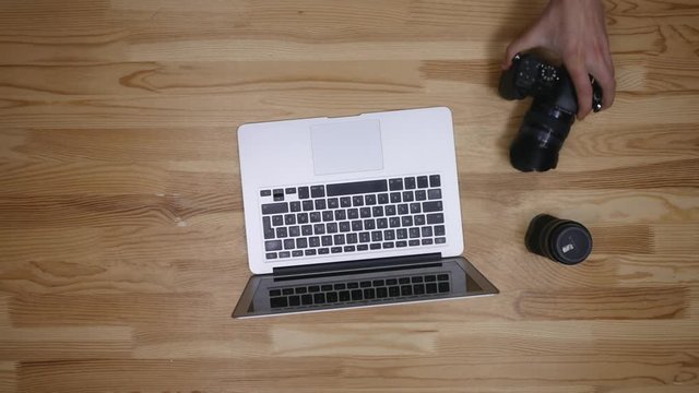 Top view of workplace photographer. A man working at the computer and drinking coffee. The items are laid out in the spirit of perfectionism on a wooden background