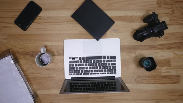 Top view of workplace photographer. A man working at the computer and drinking coffee. The items are laid out in the spirit of perfectionism on a wooden background
