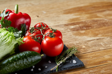 Close-up still life of assorted fresh vegetables and herbs on wooden rustic background, top view, selective focus.