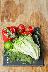 Close-up still life of assorted fresh vegetables and herbs on wooden rustic background, top view, selective focus.
