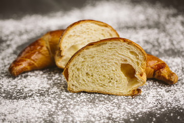 Croissant placed on a plate on a dark background.